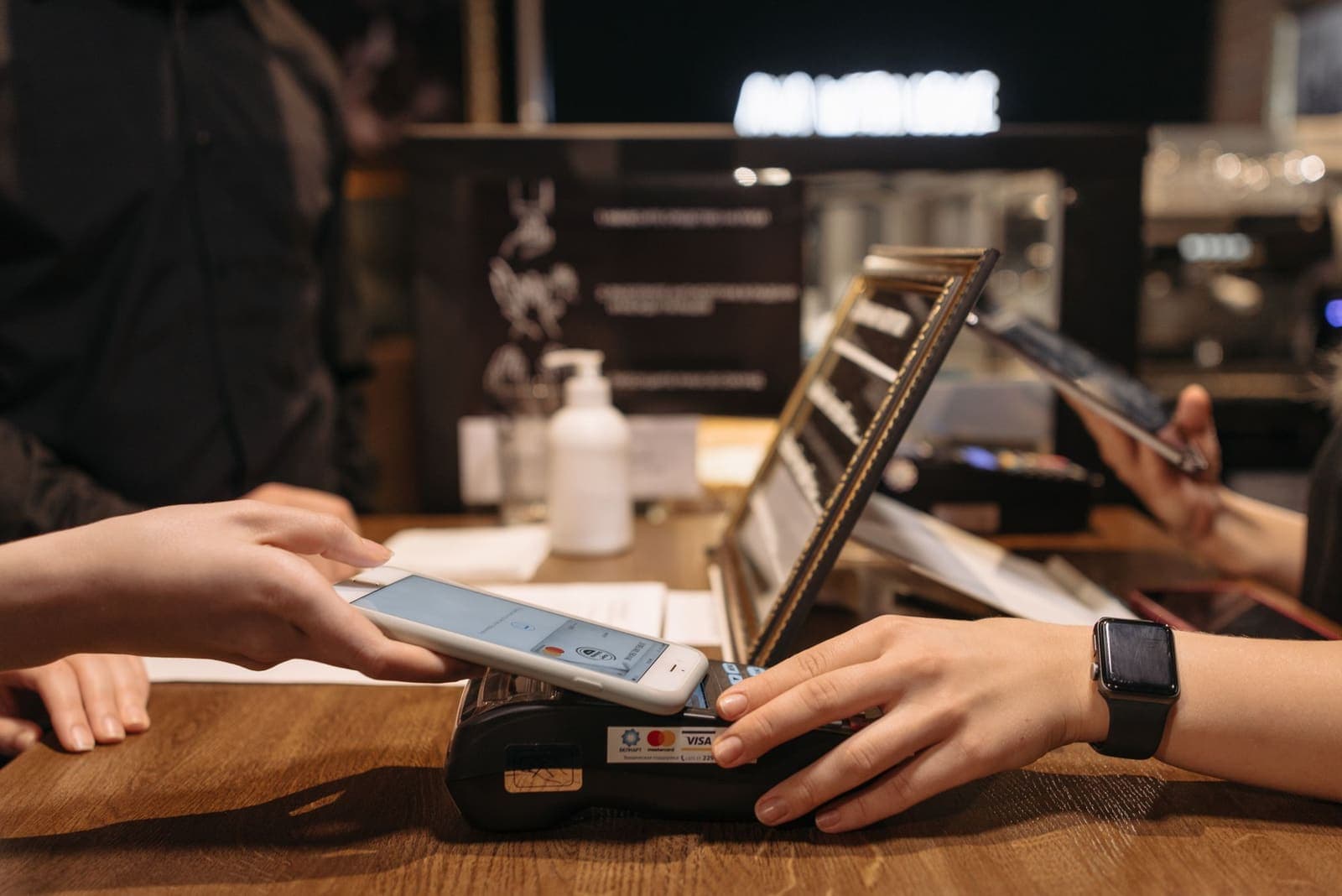 Cliente a encostar o telemóvel a um terminal ao balcão de um café